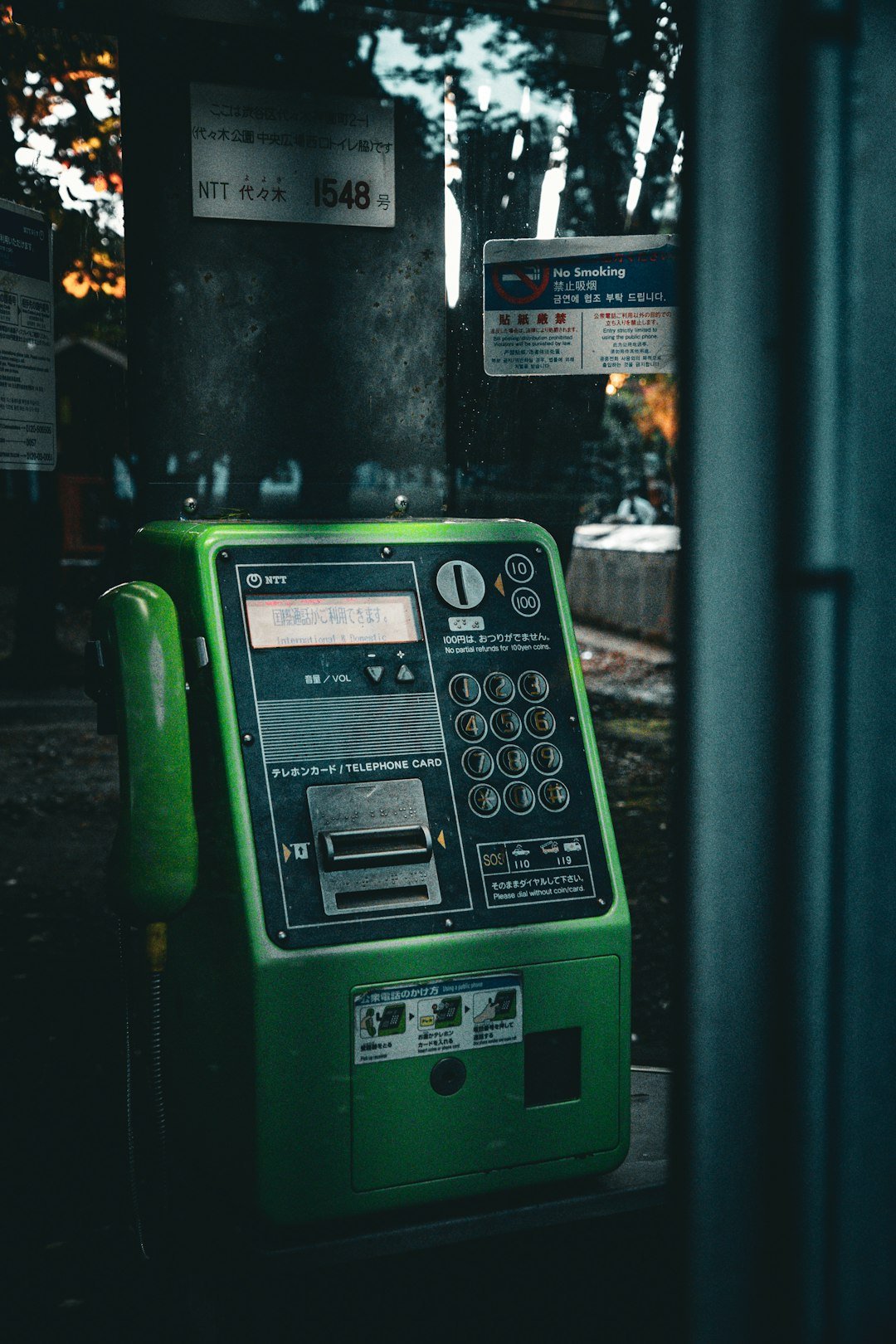 A green public telephone booth with a handset.