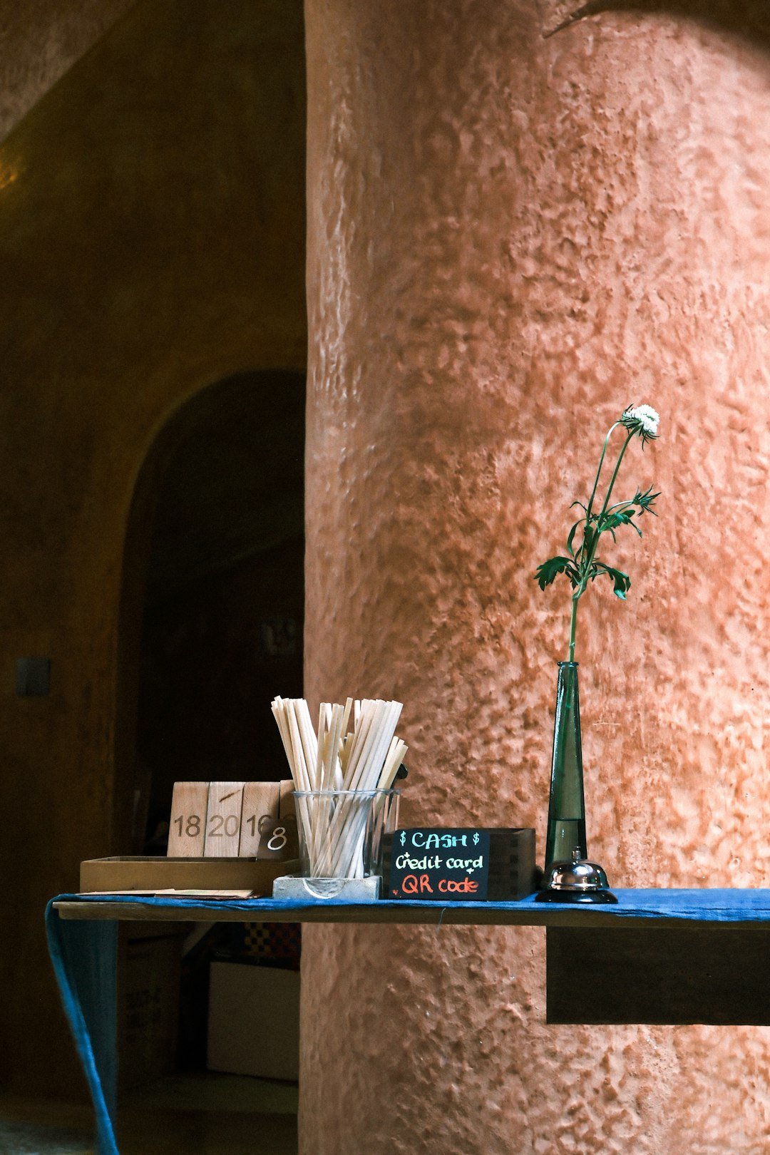 A vase with a flower and stirrers on a table.
