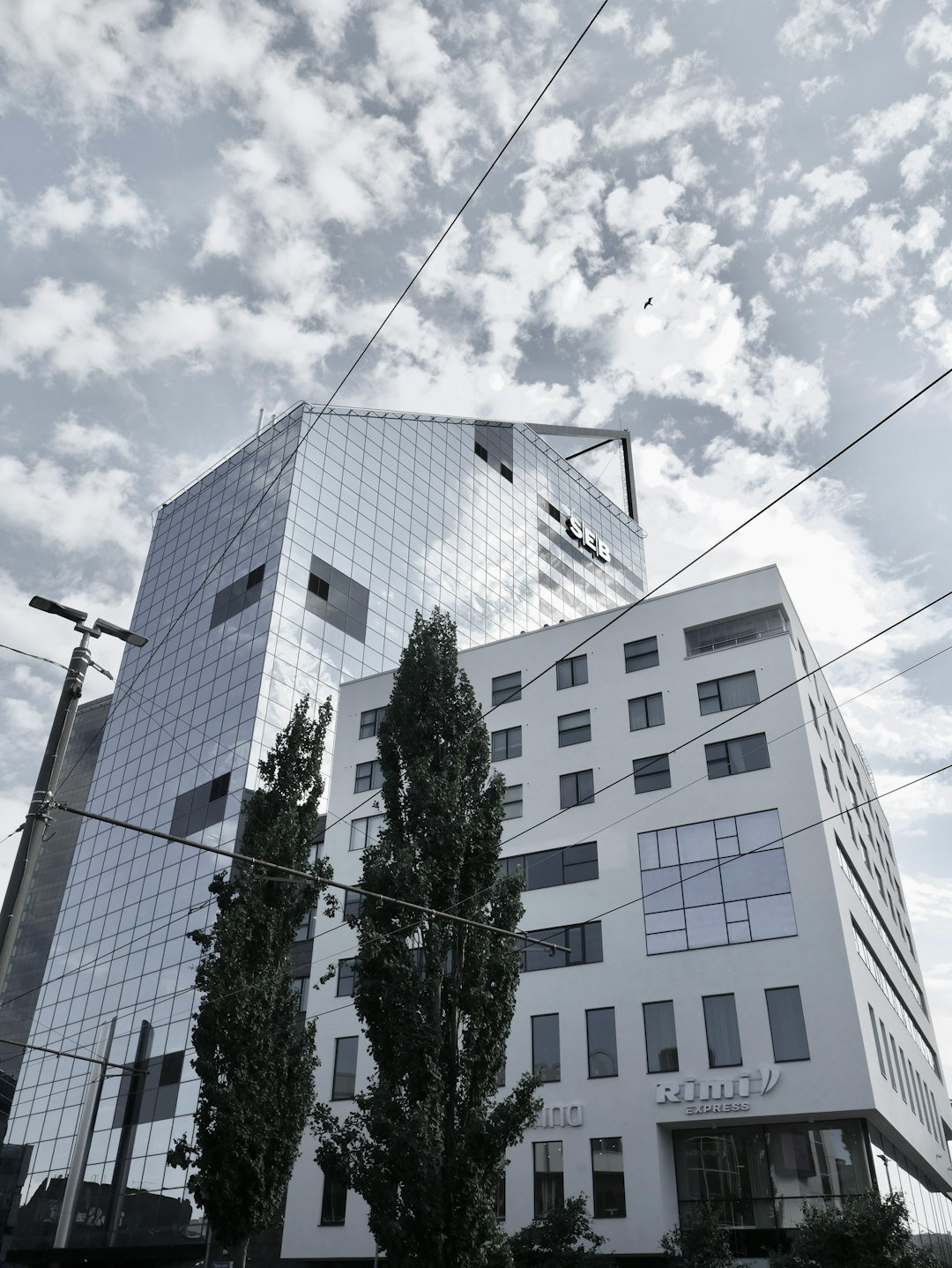Modern glass buildings against a cloudy sky.