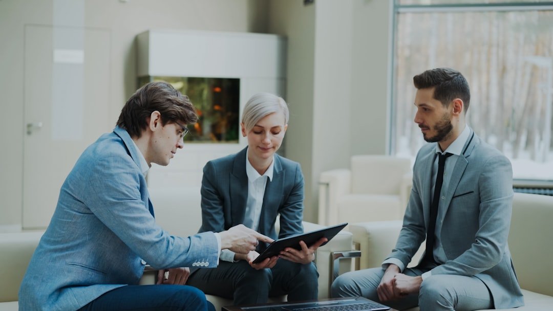 Three professionals discussing a tablet in a modern office.