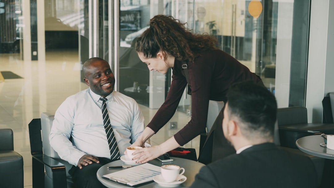 Woman serves coffee to men in office lobby.