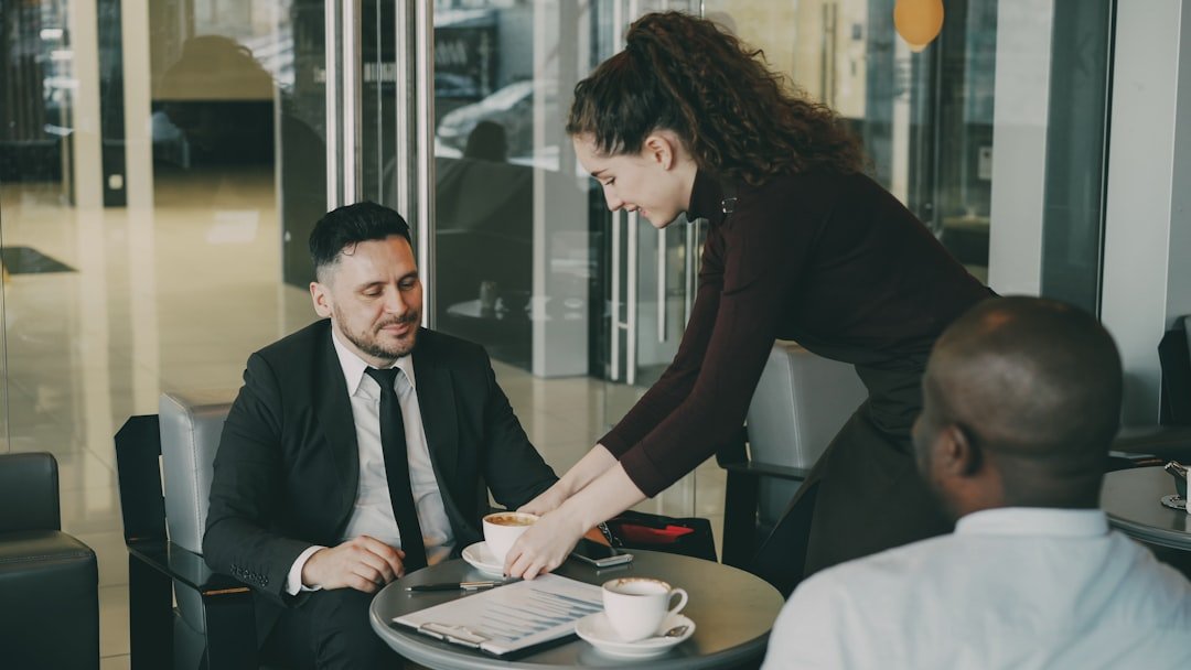Waitress serving coffee to two businessmen in cafe.