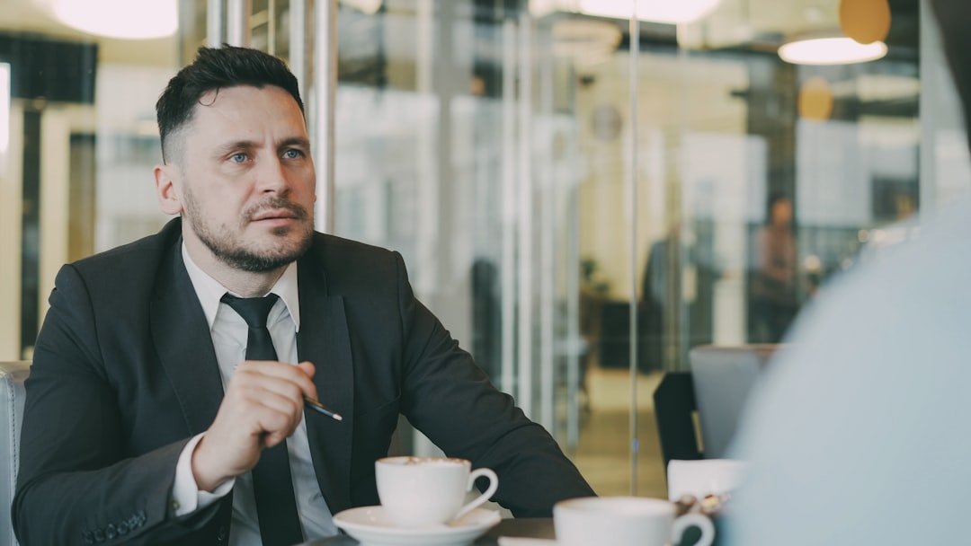 Man in suit talks at table with coffee cups.