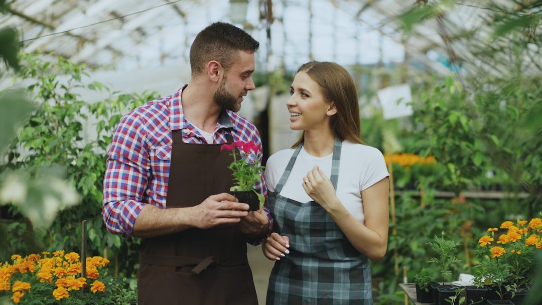 Couple holding a potted flower in a greenhouse.