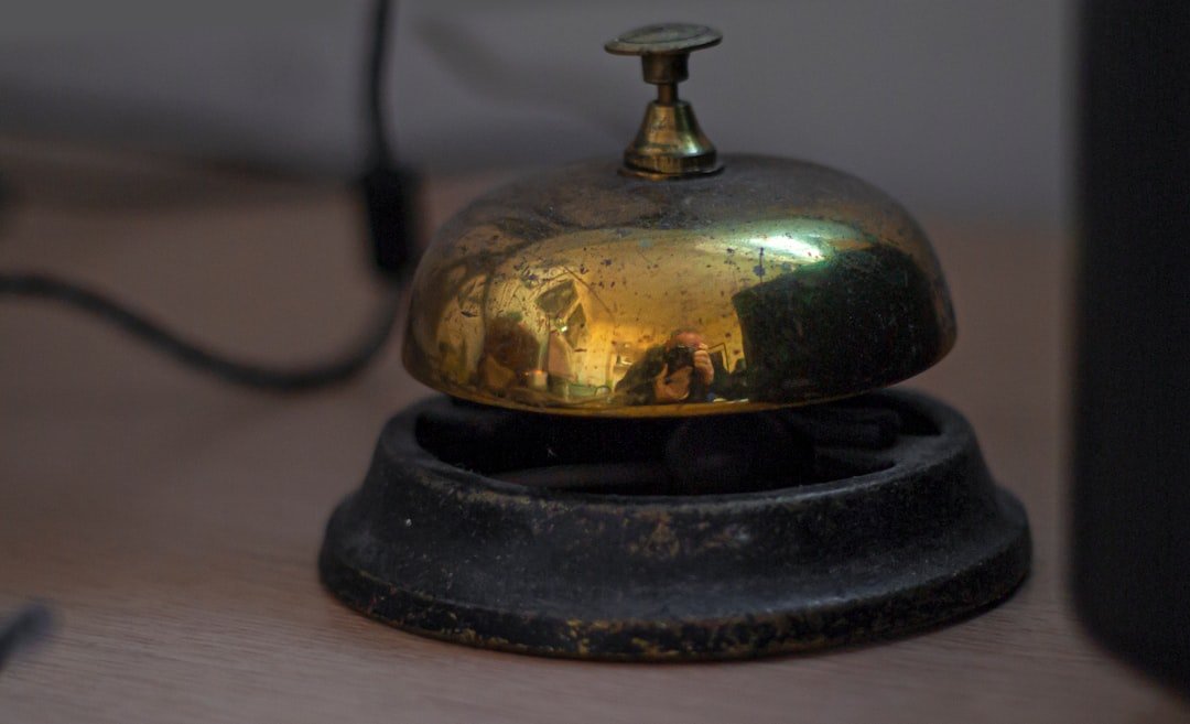 A vintage brass service bell on a wooden desk.