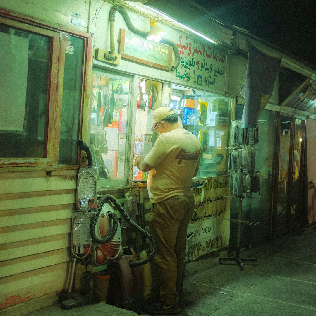Man standing at a small shop counter at night.