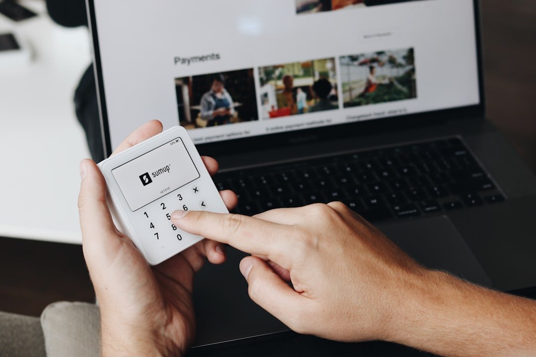 A person holding a remote control in front of a laptop