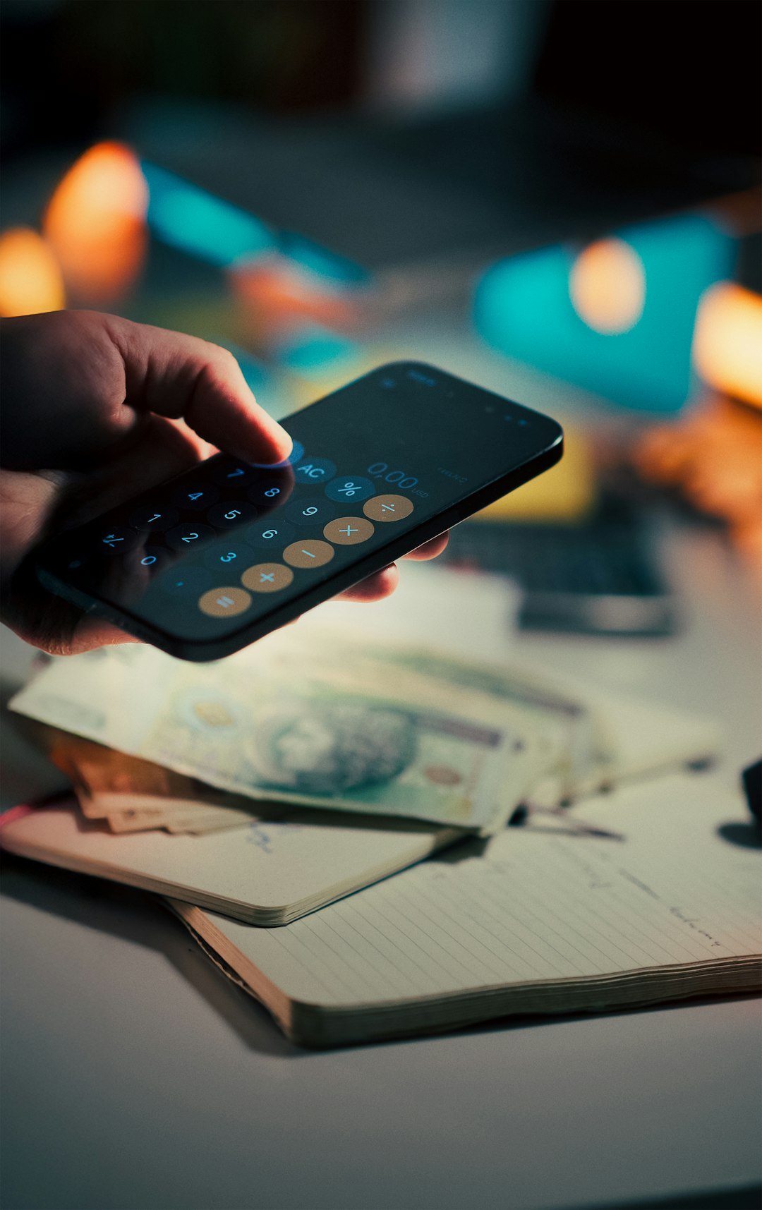 Hand using calculator on smartphone over money.