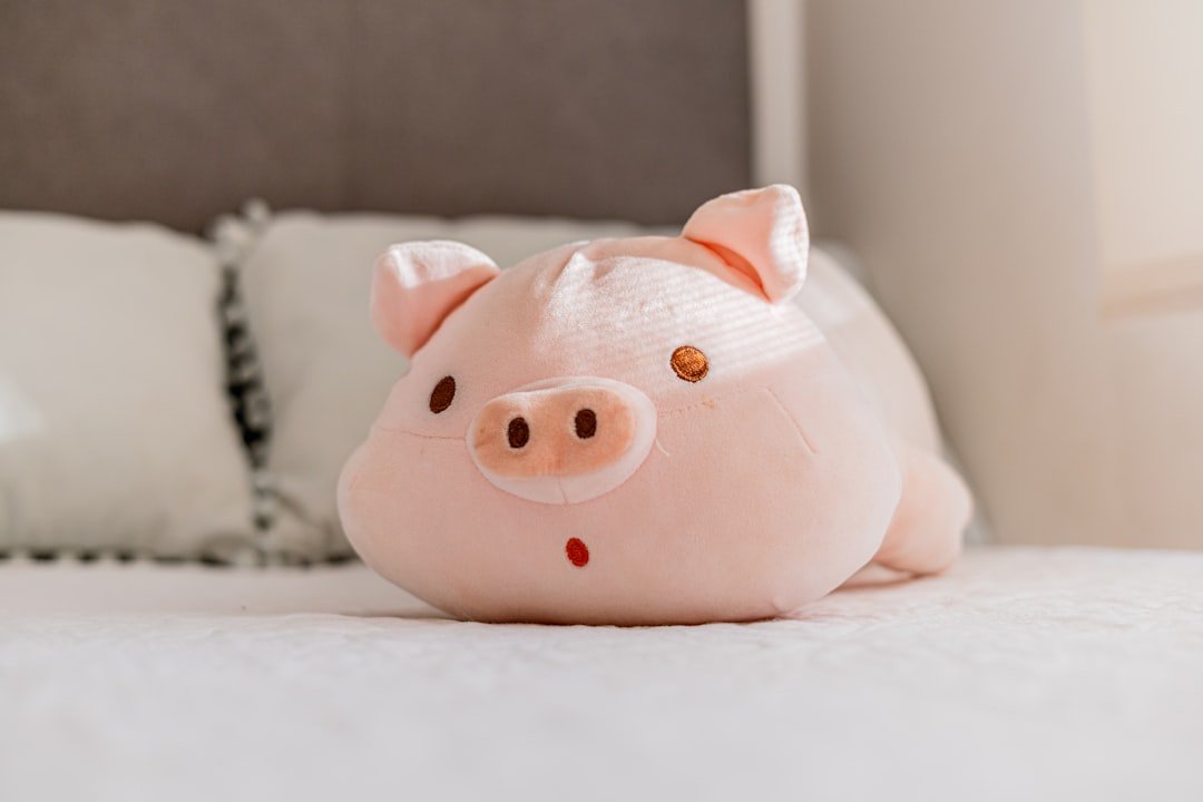 A cute pink pig plush toy on a bed.