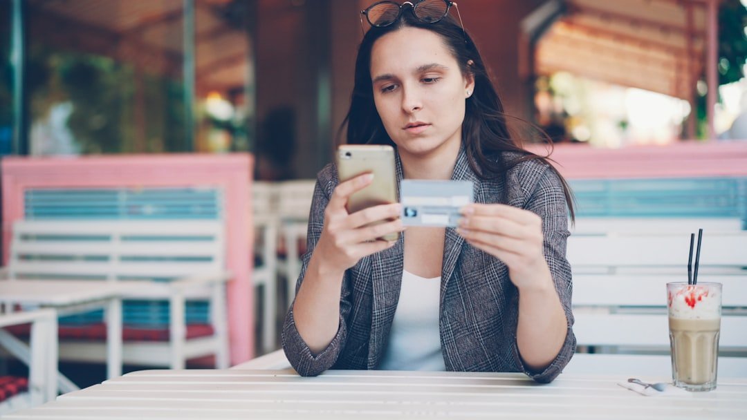 Woman holding credit card and phone at cafe