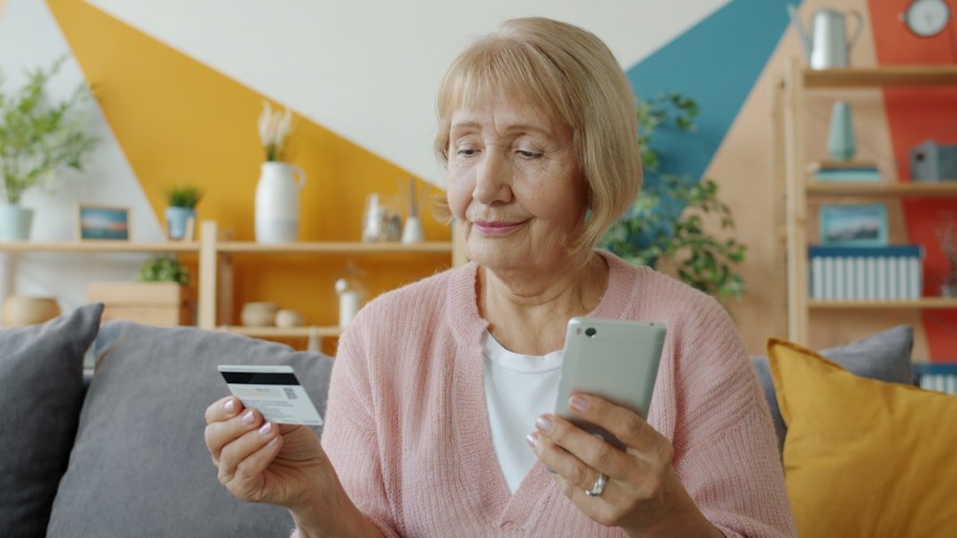 Elderly woman holding credit card and smartphone.