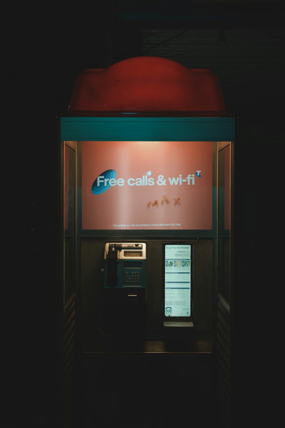 An atm machine with a red hat on top of it