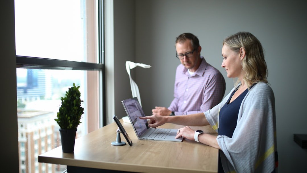 man and woman sitting at table using laptop computer