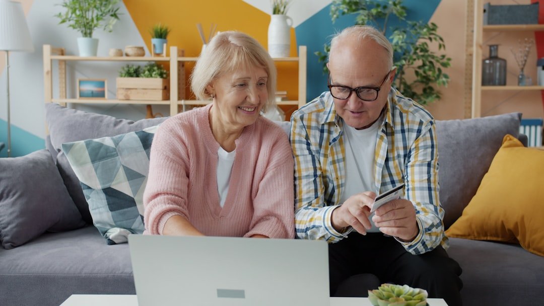 Elderly couple using laptop and credit card at home